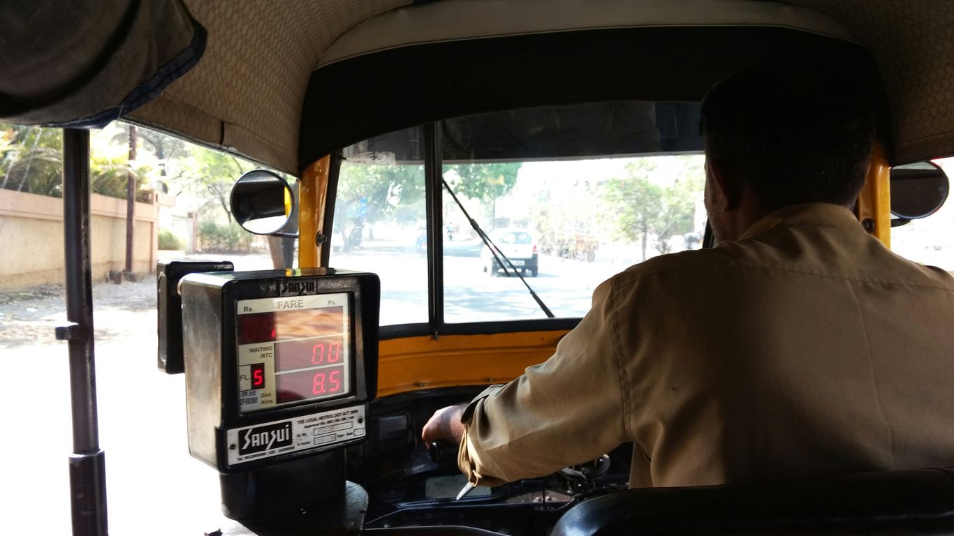 Driver operating an auto-rickshaw with a screen.