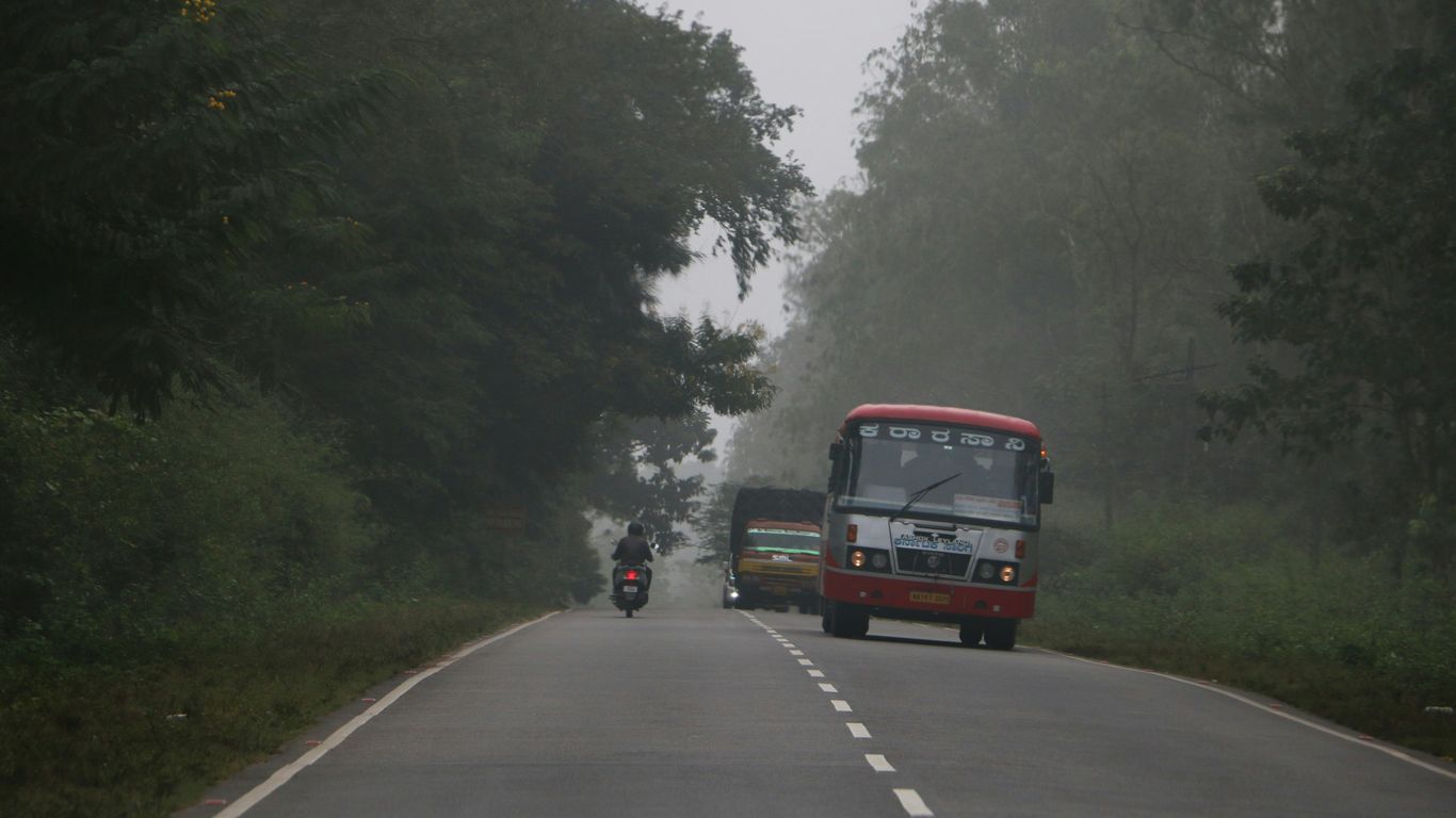 a motorcycle and bus driving down a road