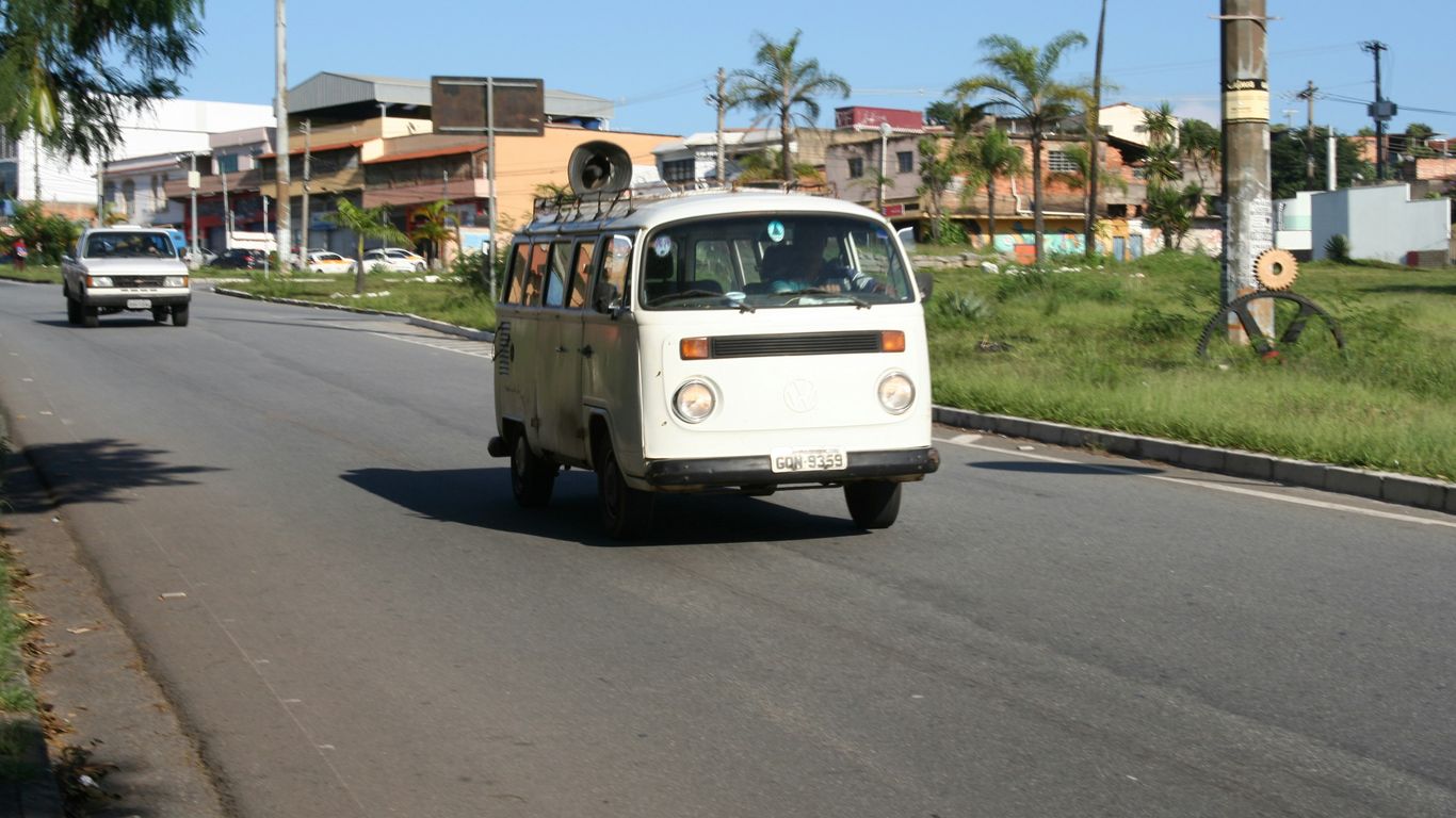 a van driving down a street next to a lush green field